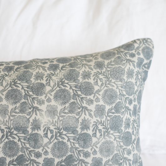 Blue and cream lumbar pillow with floral botanical print featuring rounded flowers and leafy stems throughout.