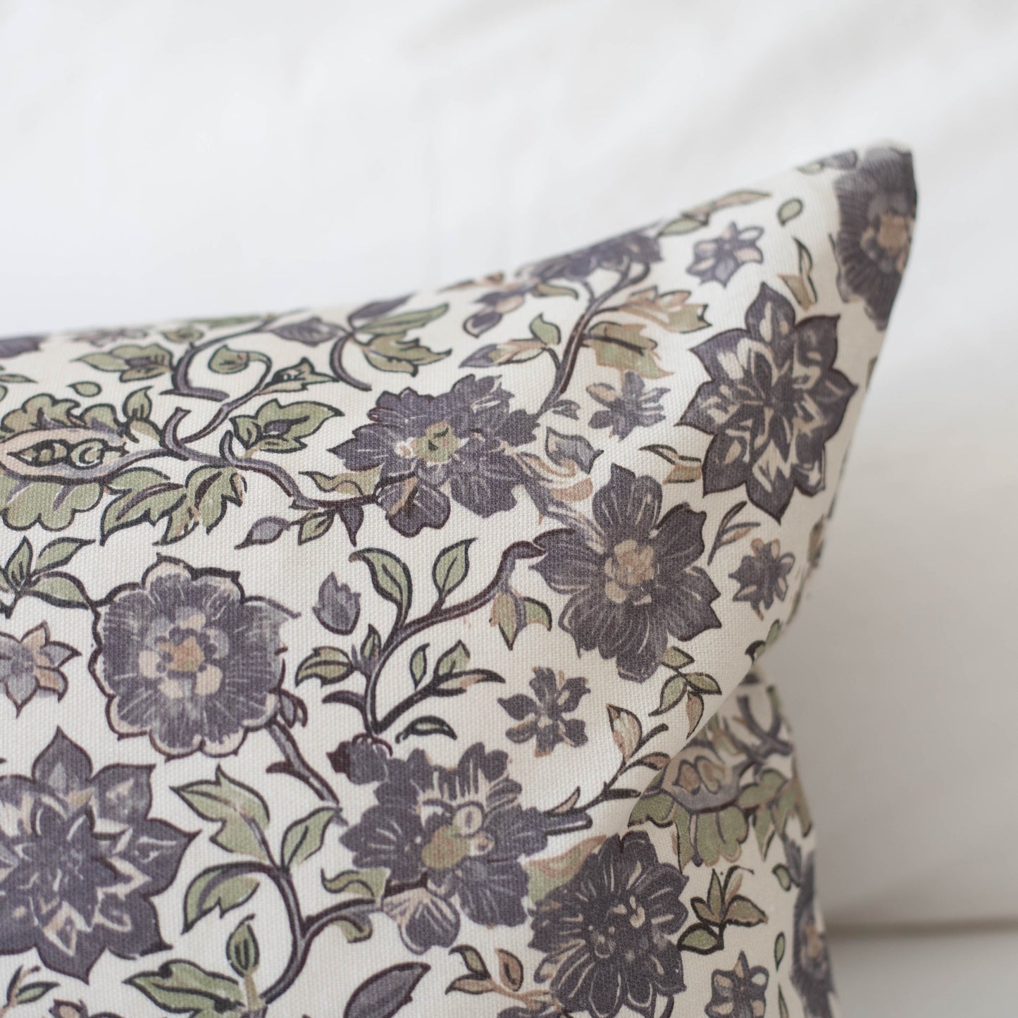 Cream pillow with dark blue and gray floral pattern featuring scrolling vines and layered flowers.
