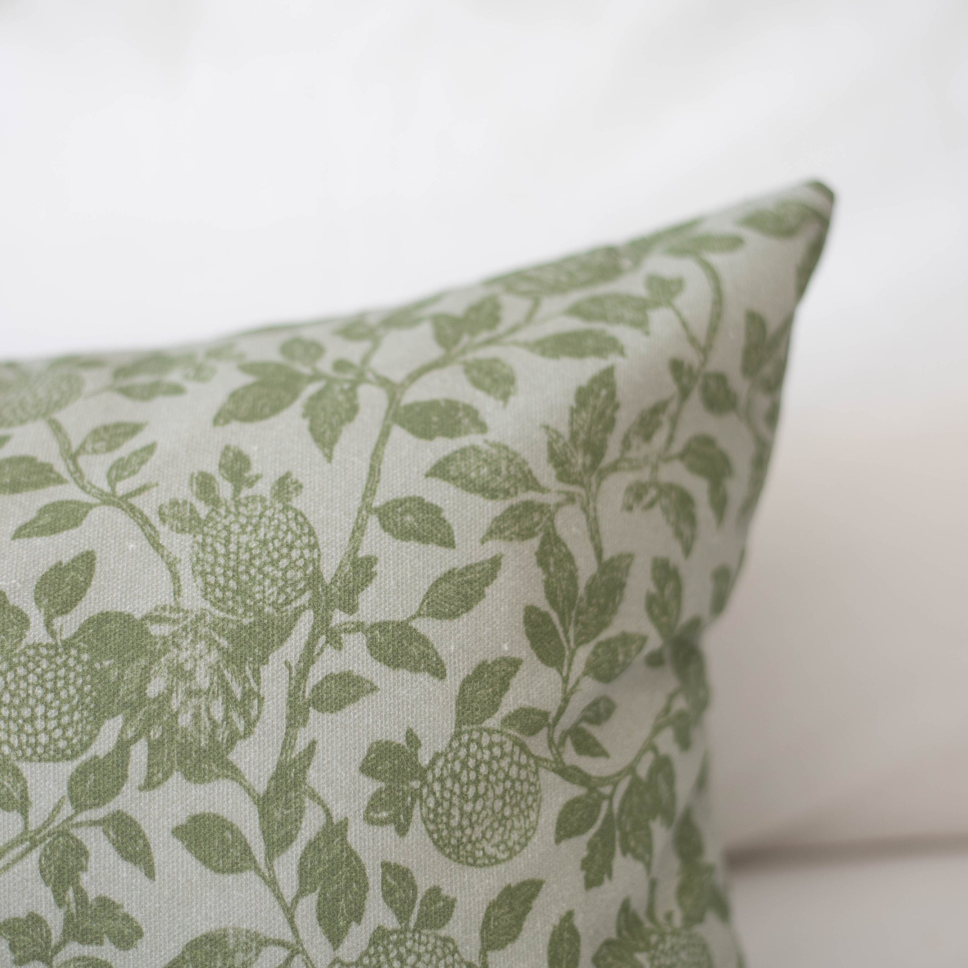 Cream pillow with sage green ivy and fruit botanical pattern on natural linen fabric.