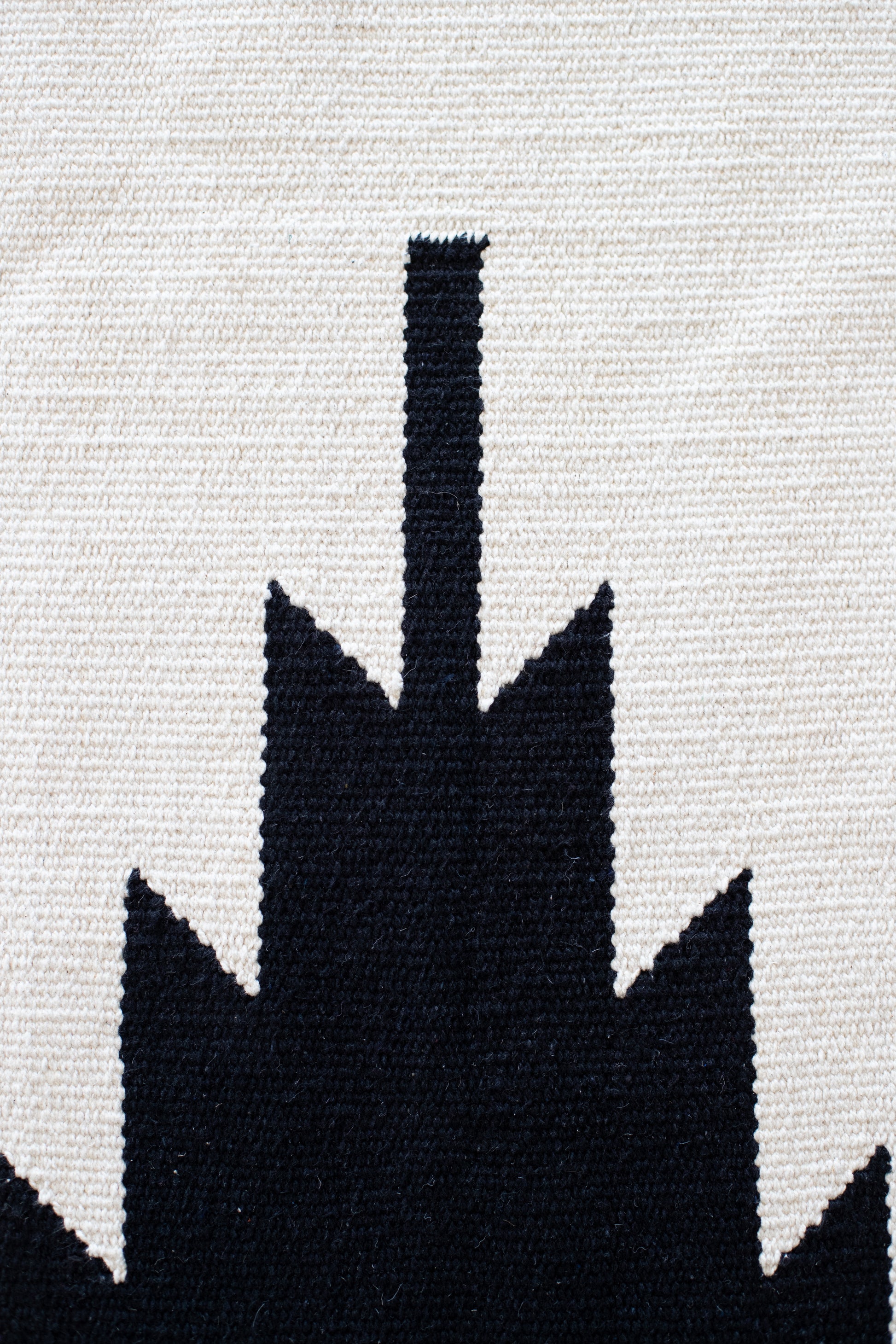 Cream and black woven rug with saguaro cactus silhouette design.
