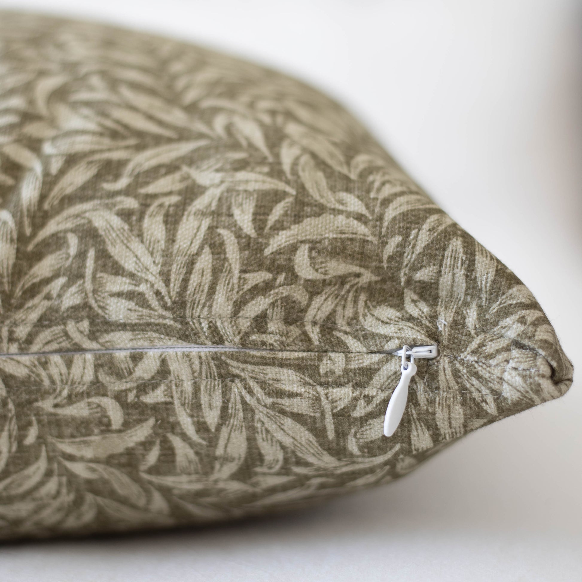Rectangular pillow with tan and cream leaf pattern fabric and white zipper closure.