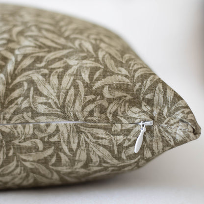 Rectangular pillow with tan and cream leaf pattern fabric and white zipper closure.