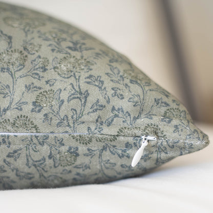 Green pillow with blue floral pattern and white zipper detail visible on seam.