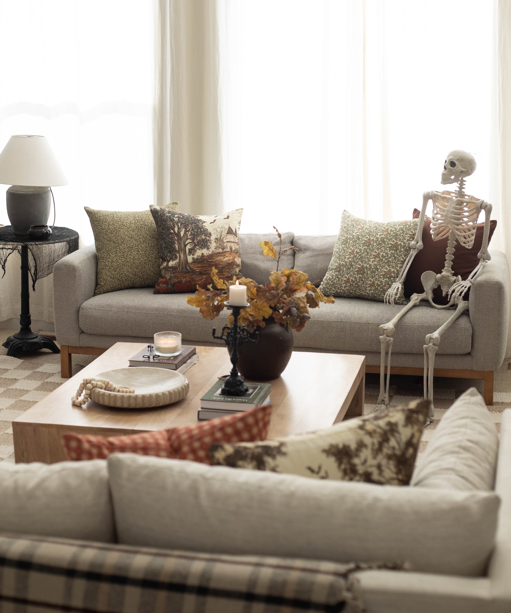 Linen throw pillow with autumn harvest scene featuring bare tree and falling leaves in brown and gold tones.