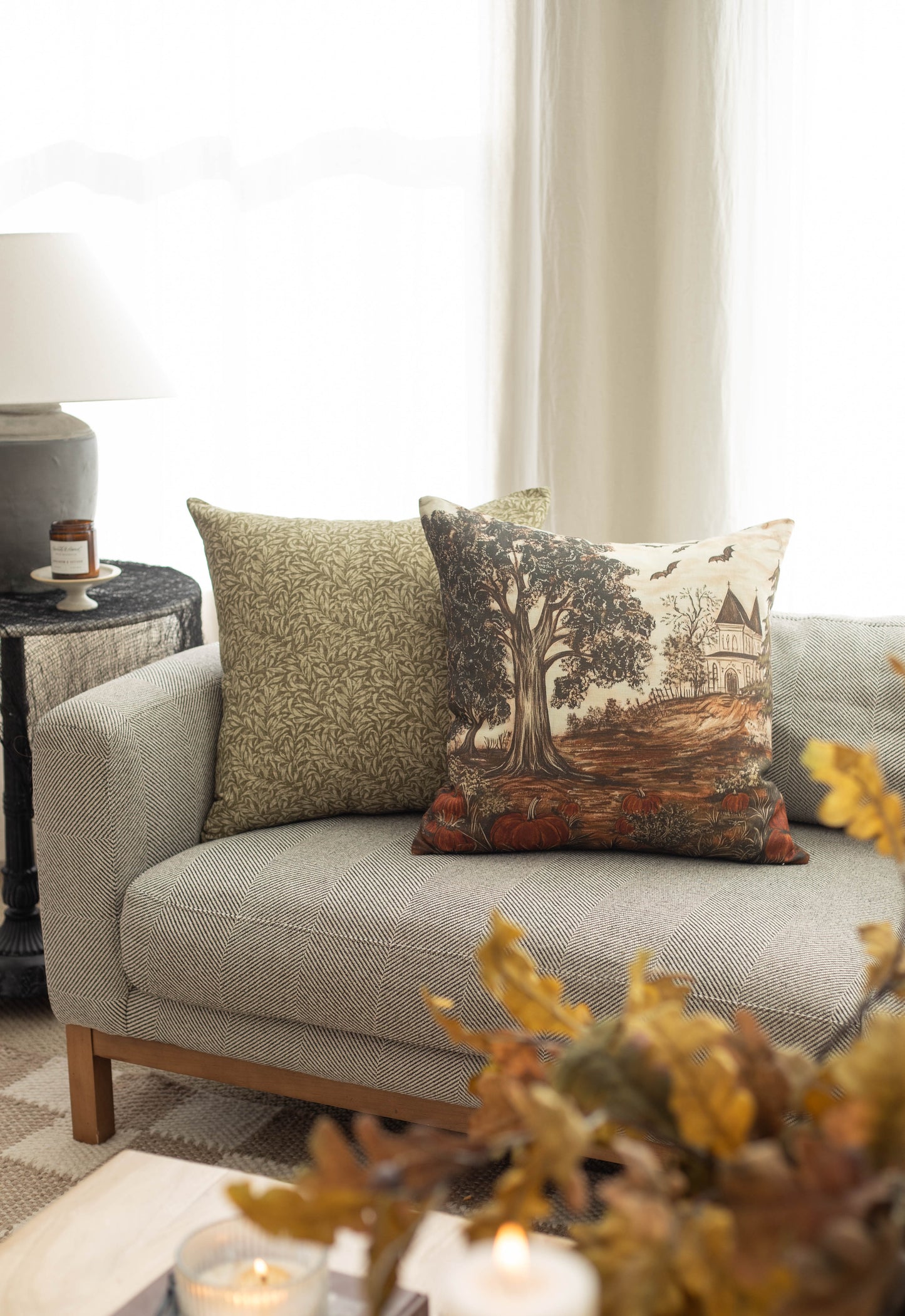 Linen throw pillow with haunted house and gnarled tree design in cream, brown, and rust tones.
