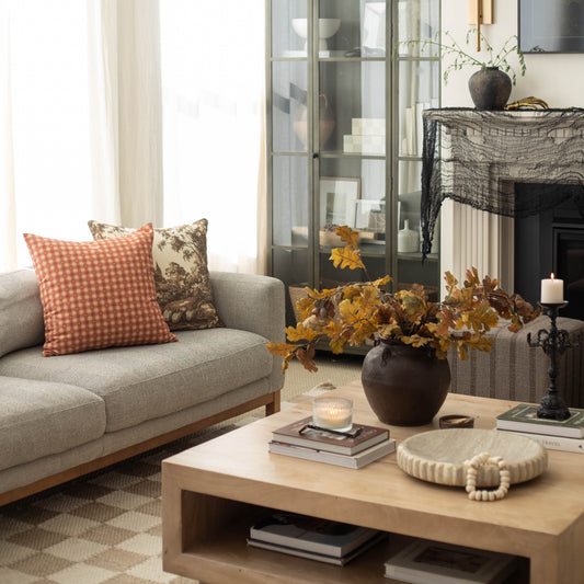 Orange and white gingham plaid throw pillow on beige sofa.