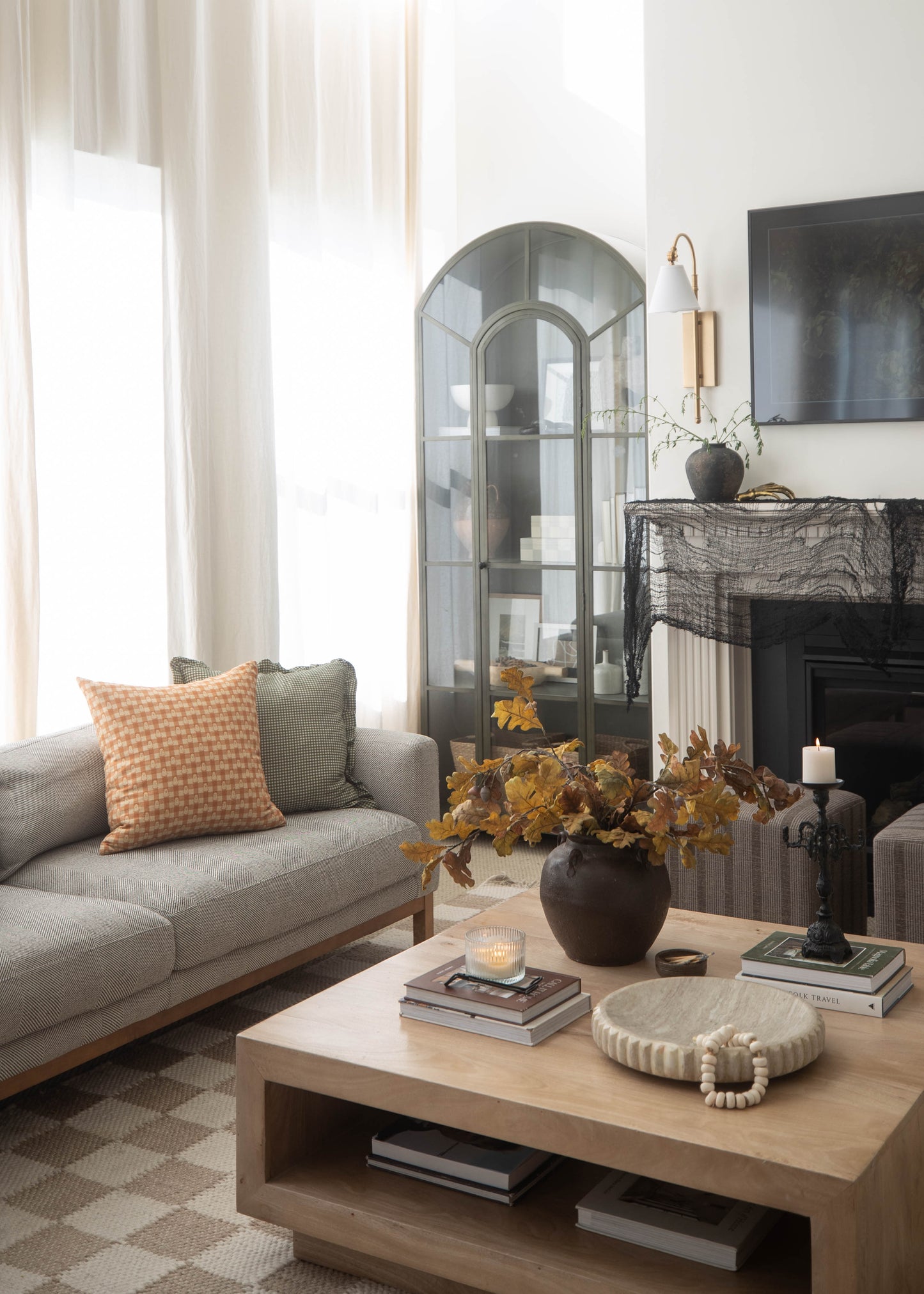 Orange and cream gingham patterned pillow on gray upholstered sofa in modern living room setting.