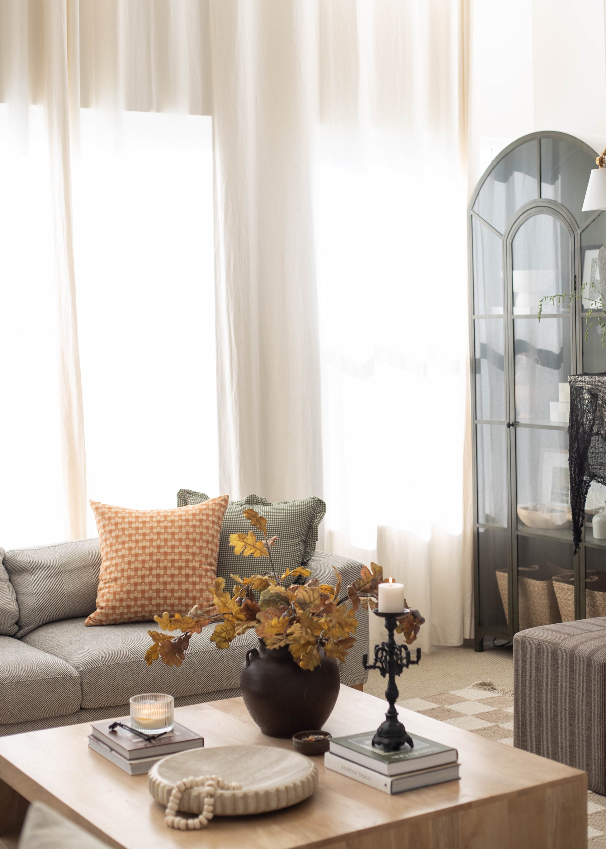 Orange and white gingham patterned pillow displayed on a gray sofa in a living room setting.