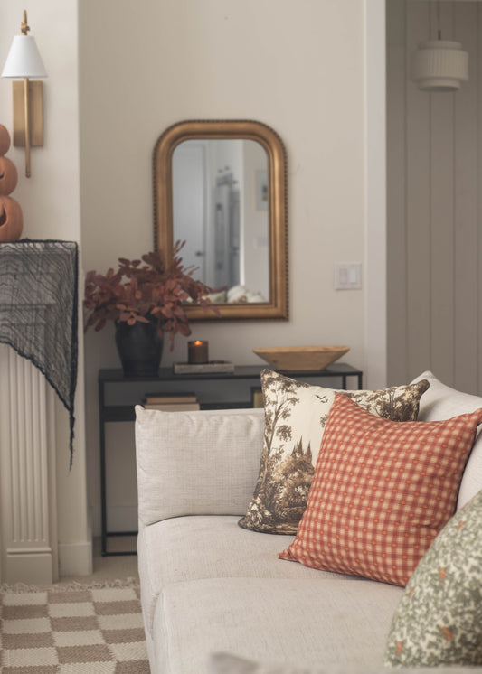 Arched wooden-framed mirror with gold finish hanging above black console table in home interior.
