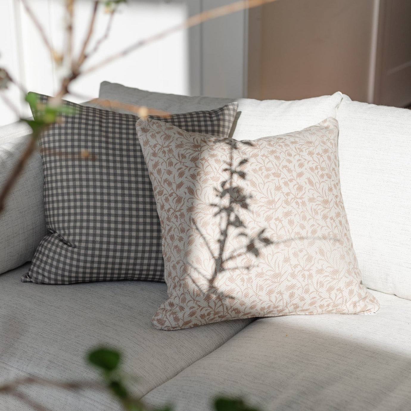 Brown and white gingham patterned pillow displayed on a gray sofa with coordinating pillows.