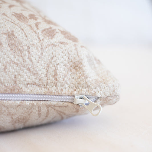 Beige and cream thick weave pillow cover with concealed zipper closure and textured fabric surface.