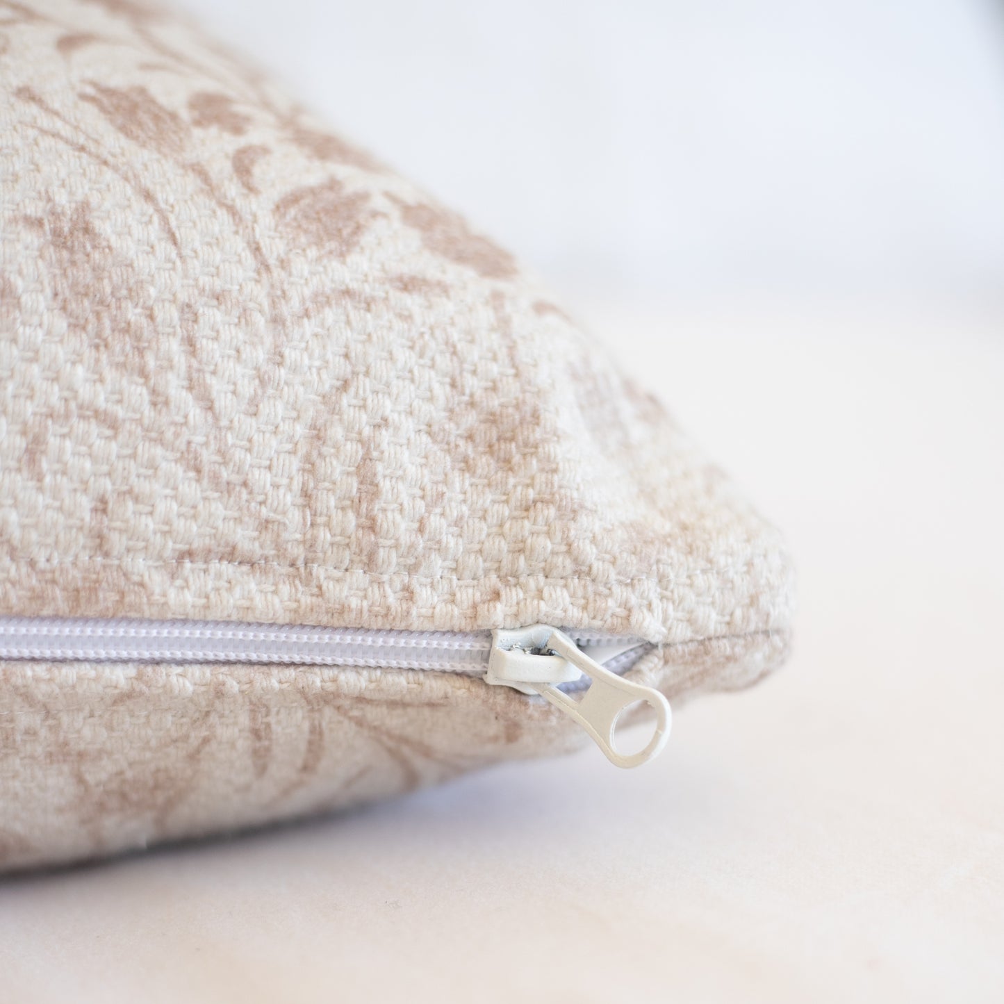Beige textured pillow cover with visible zipper closure and thick woven fabric.