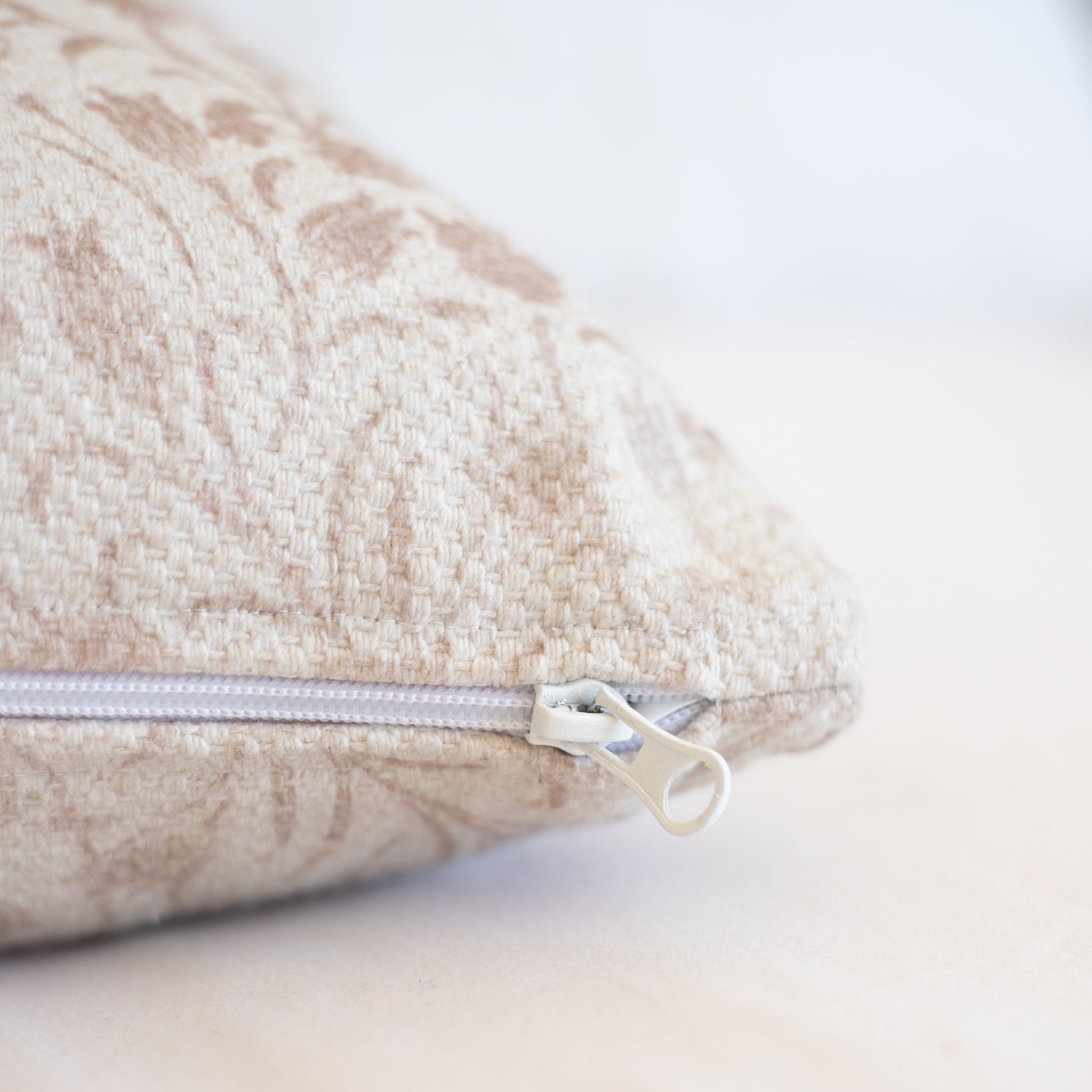 Beige textured pillow cover with visible zipper closure and thick woven fabric.