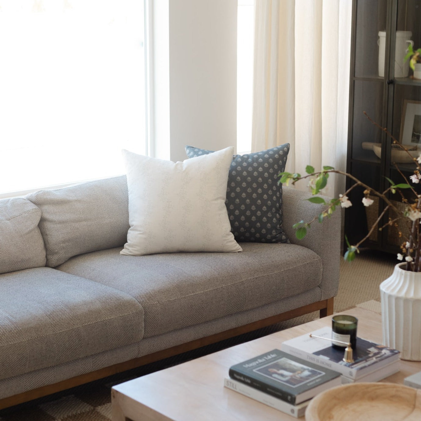 Blue and white patterned throw pillow displayed on gray upholstered sofa.