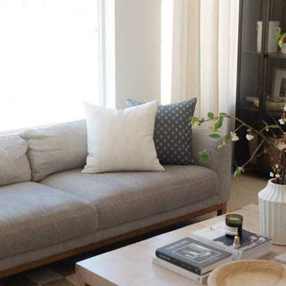 Blue and white patterned throw pillow displayed on gray upholstered sofa.