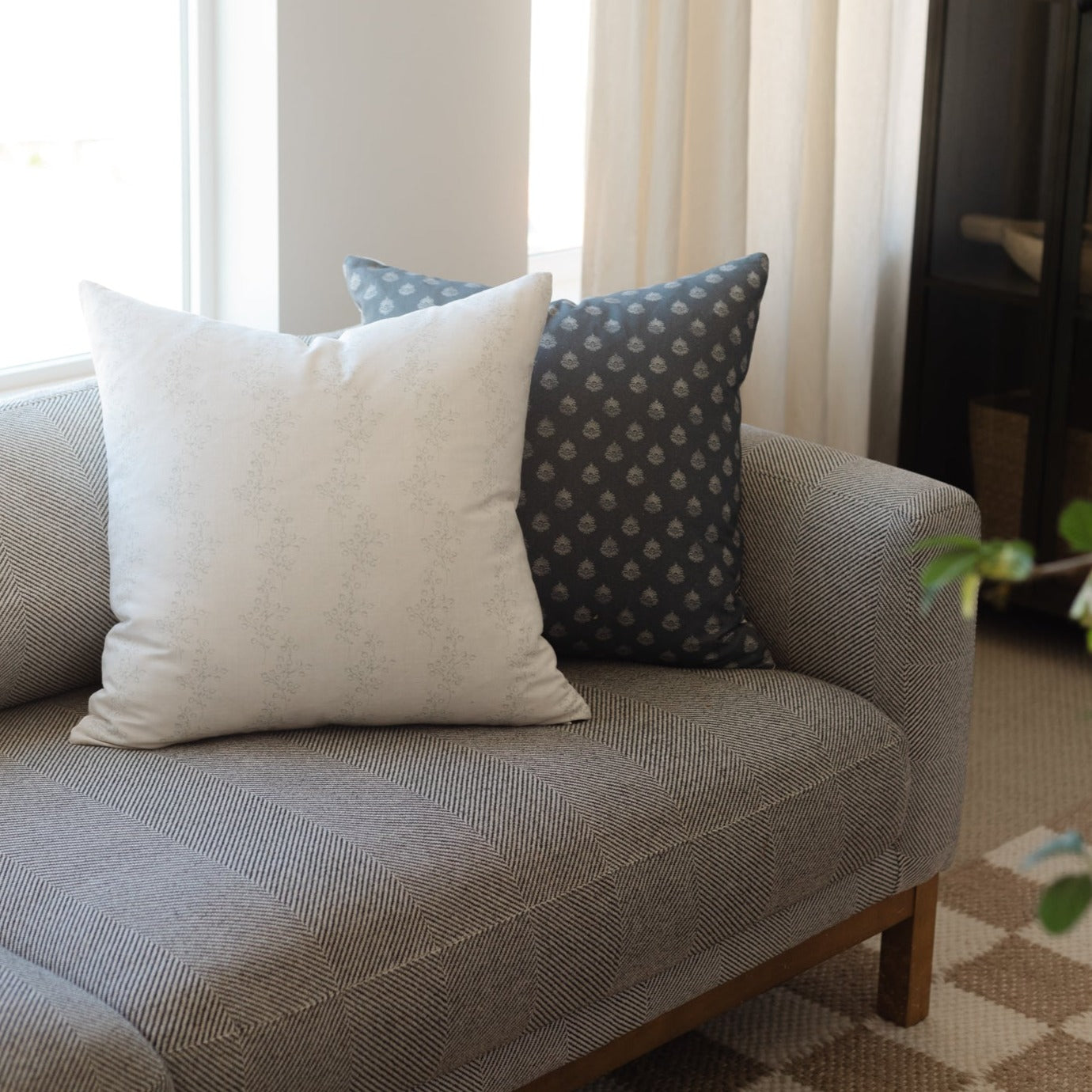 Blue vintage-patterned decorative pillows arranged on a gray upholstered chair with wooden legs.
