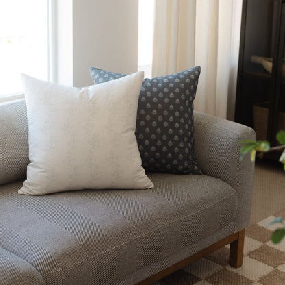 Blue vintage-patterned decorative pillows arranged on a gray upholstered chair with wooden legs.