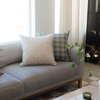 Cream and taupe patterned pillow with textured weave fabric displayed on gray upholstered sofa.