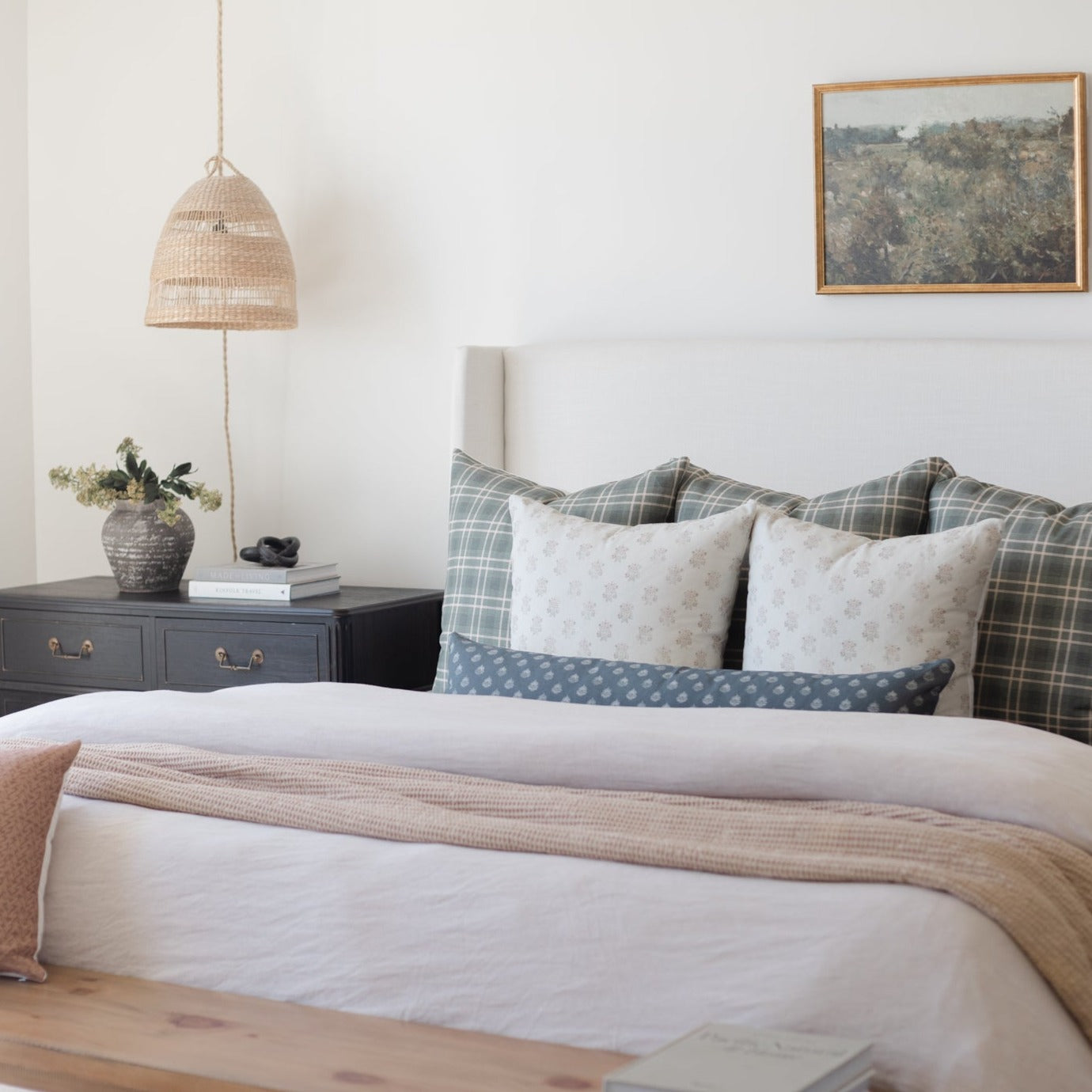 Woven rattan pendant light with natural finish hanging above a bedroom nightstand.