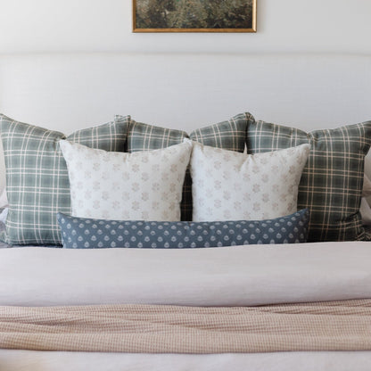 Blue lumbar pillow with geometric pattern displayed on bed with coordinating pillows and bedding.