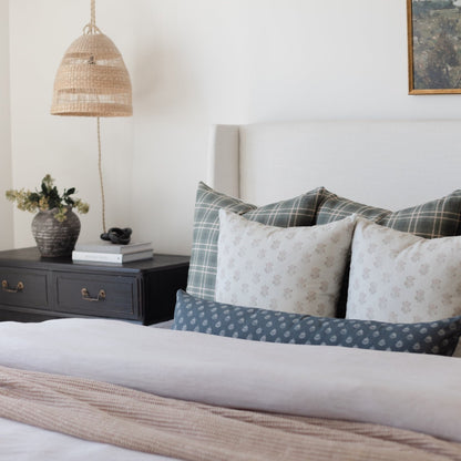 Woven pendant lamp with natural rattan shade hanging above a bedside table in a bedroom setting.