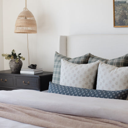 Woven pendant lamp with natural rattan dome shade hanging above bedroom nightstand.