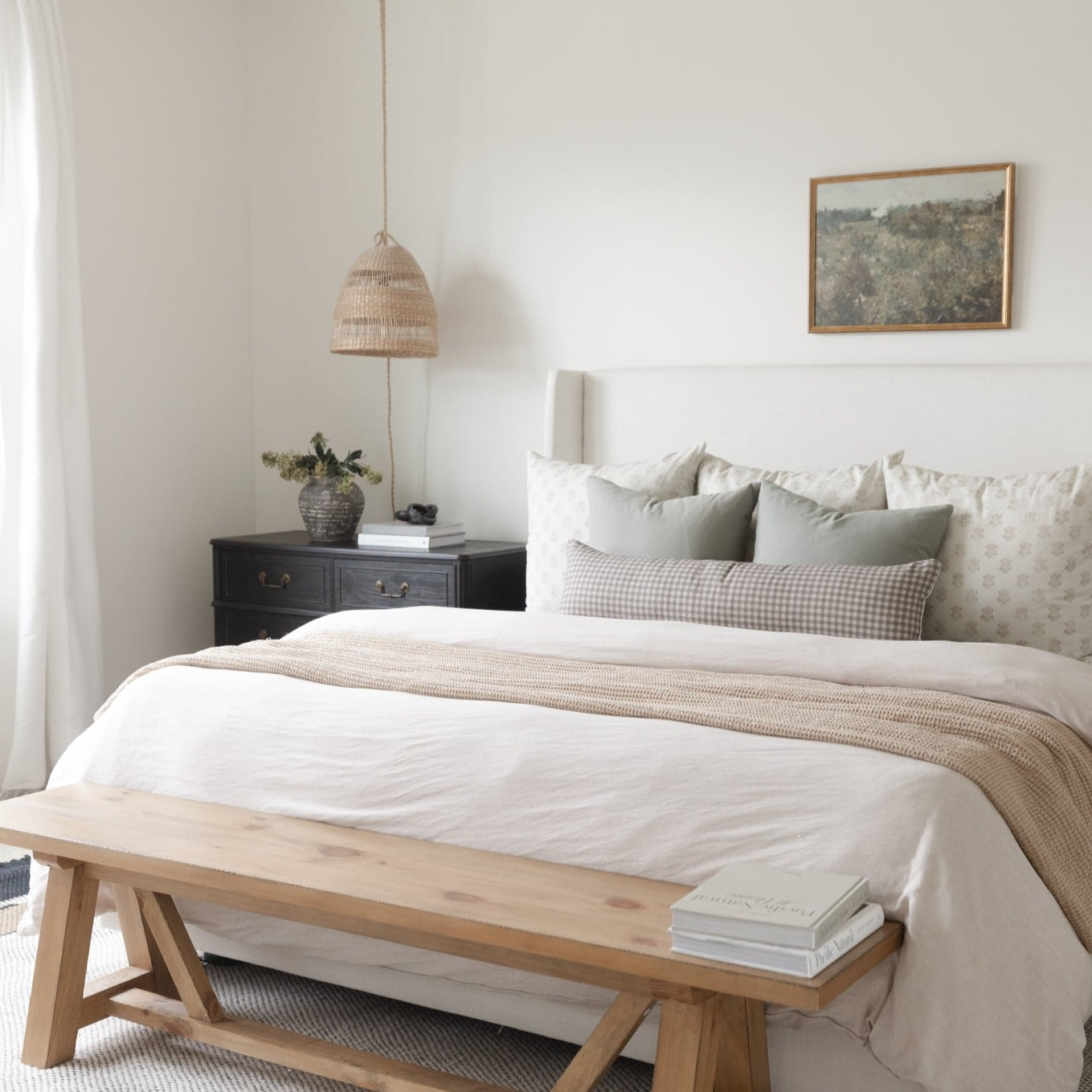 Brown gingham lumbar pillows displayed on a bed with white and neutral bedding in a styled bedroom.