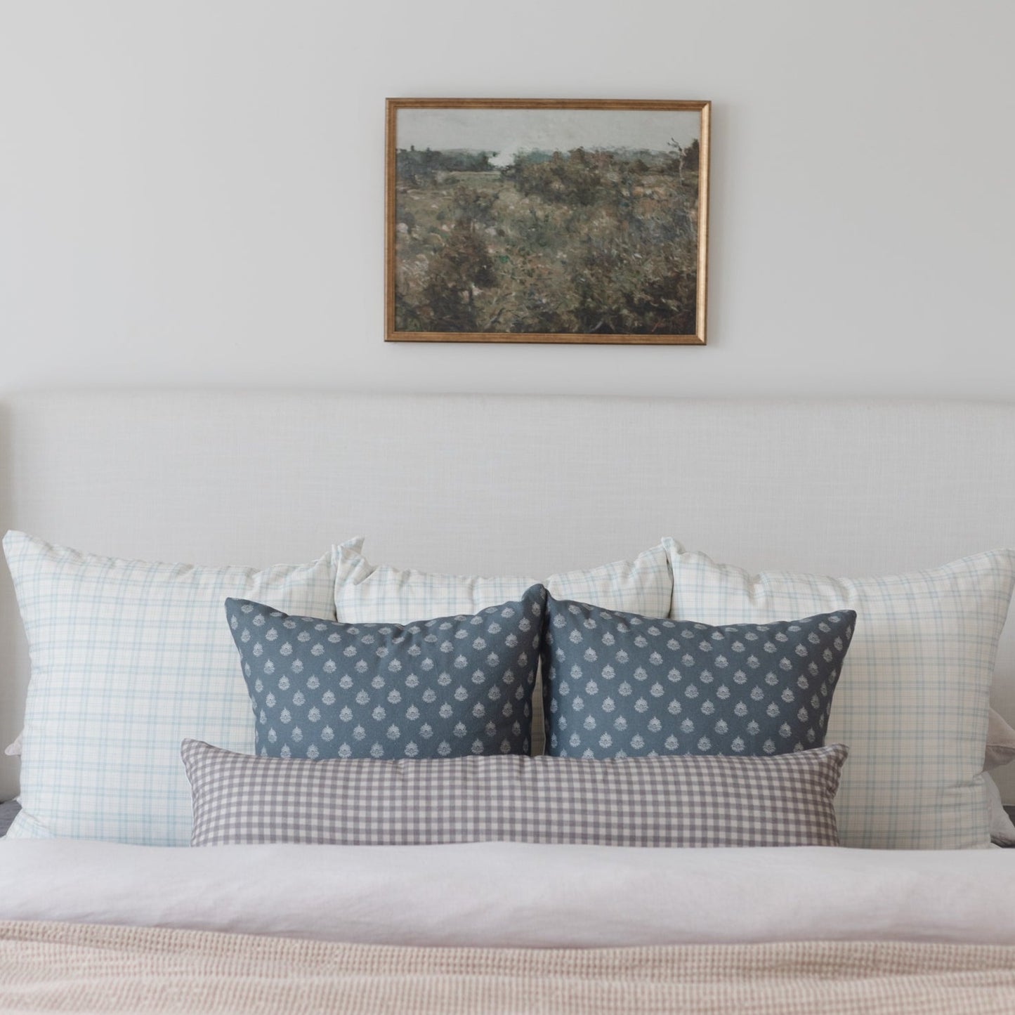 Brown and white gingham lumbar pillow displayed on a bed with coordinating pillows.