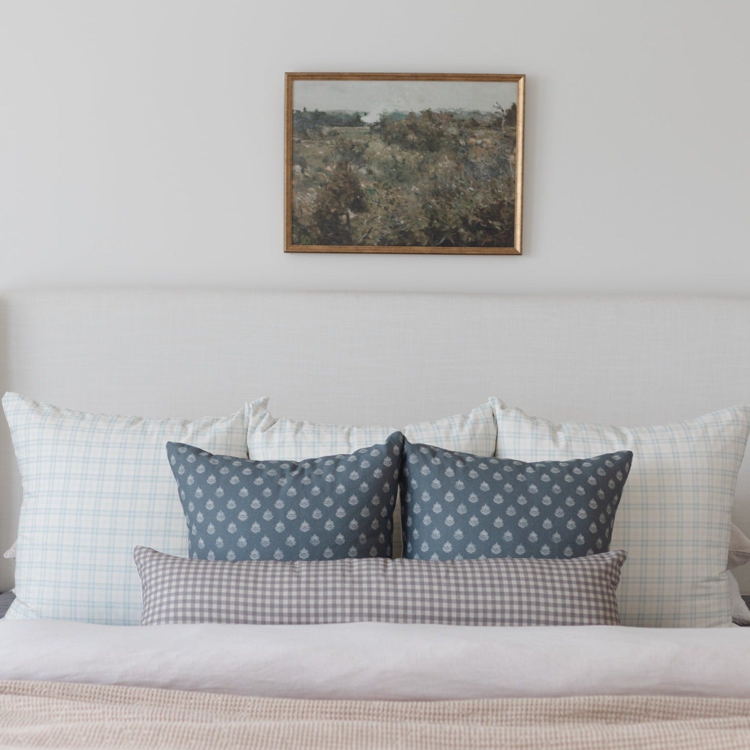 Brown and white gingham lumbar pillow displayed on a bed with coordinating pillows.