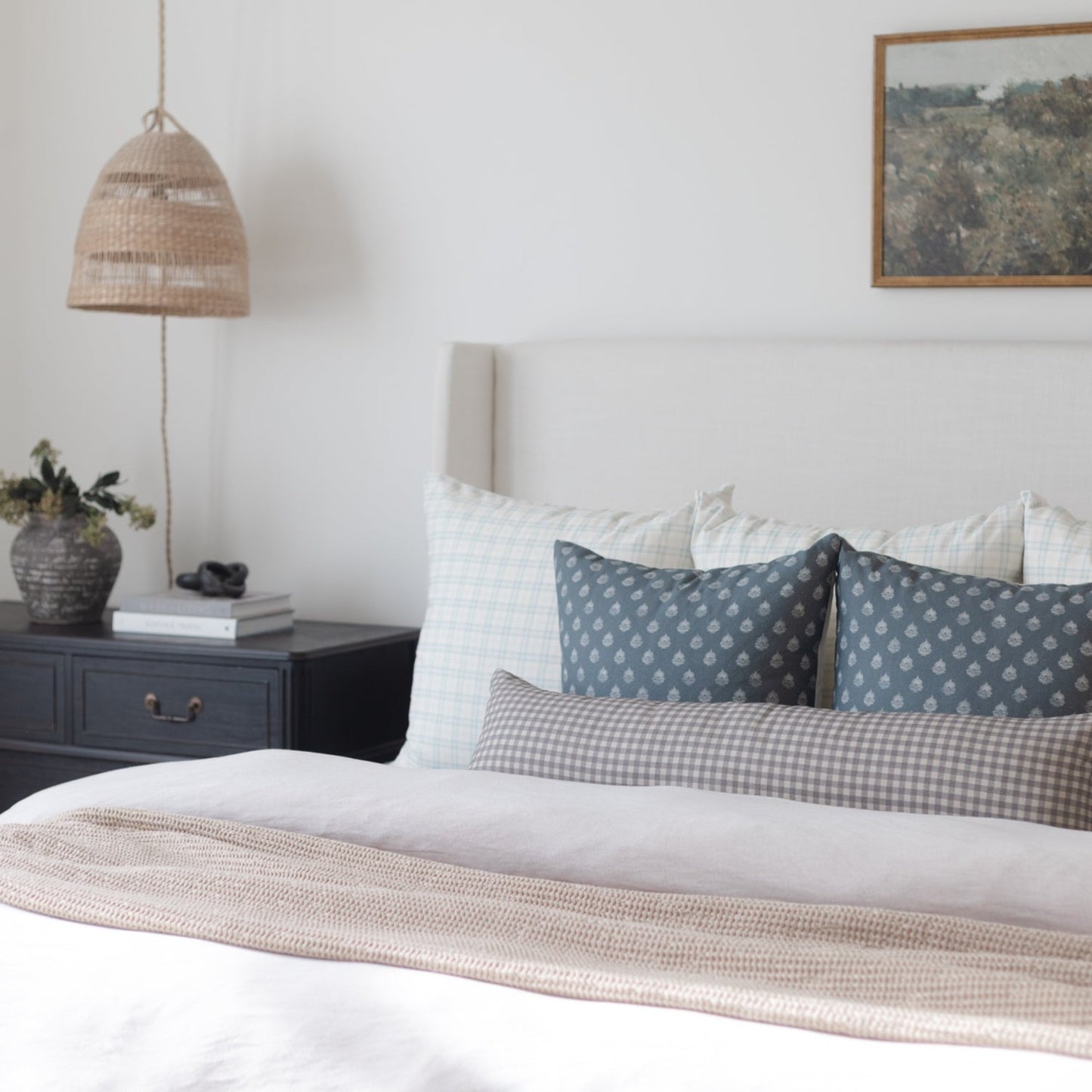 Two blue patterned throw pillows displayed on a bed with white and gray bedding.