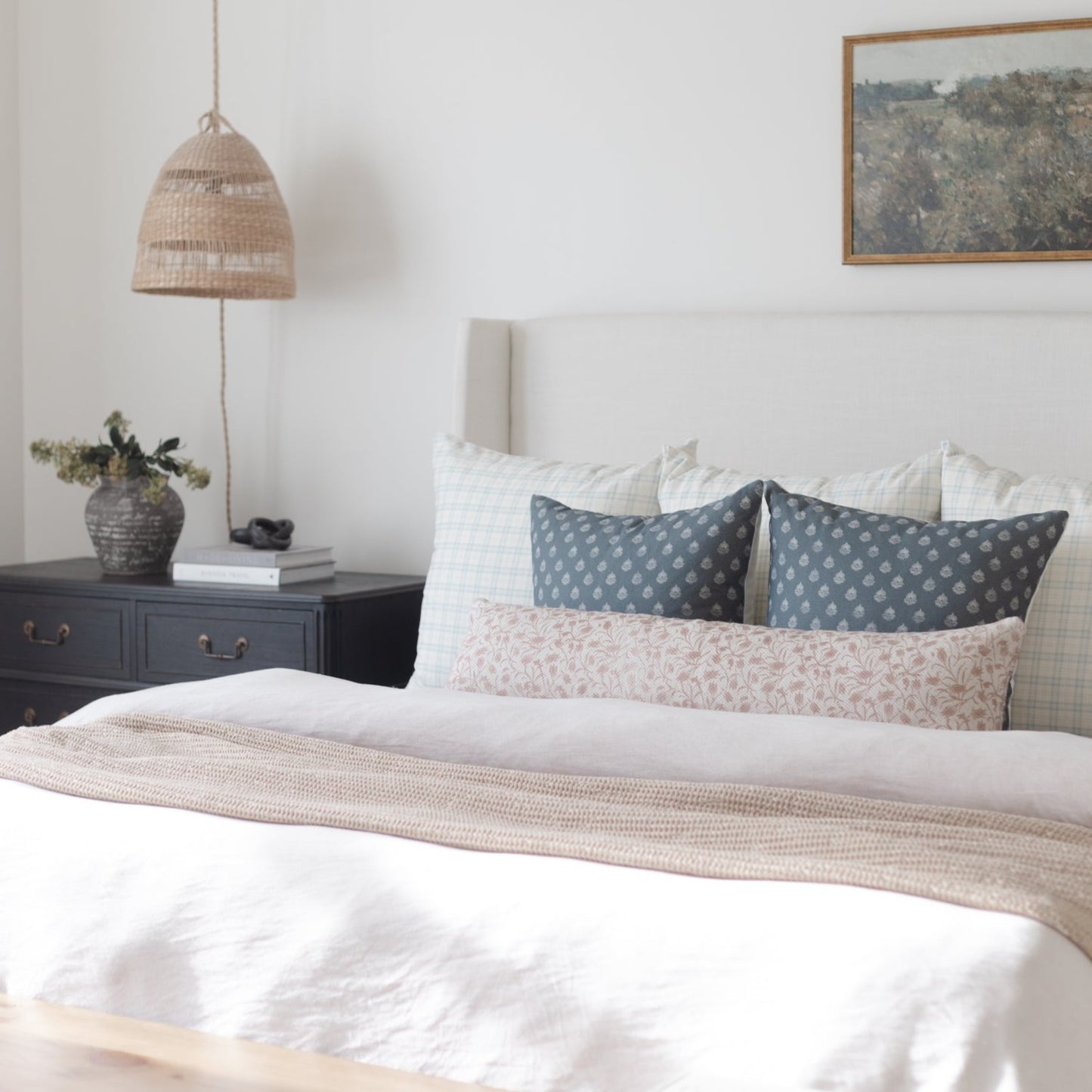 Woven pendant lamp with natural fibers hanging above a bedroom nightstand.