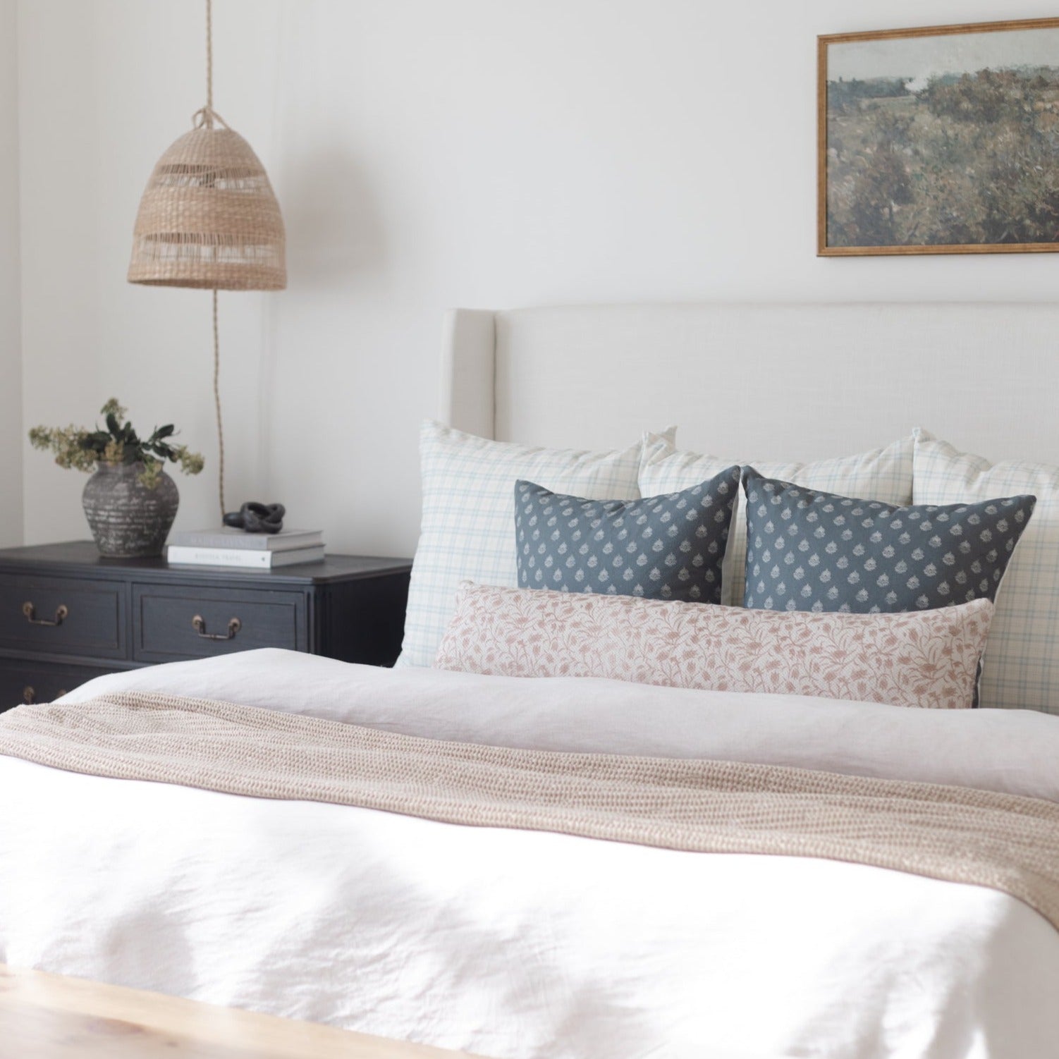 Woven pendant lamp with natural fibers hanging above a bedroom nightstand.