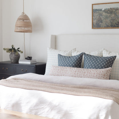 Woven pendant lamp with natural fibers hanging above a bedroom nightstand.