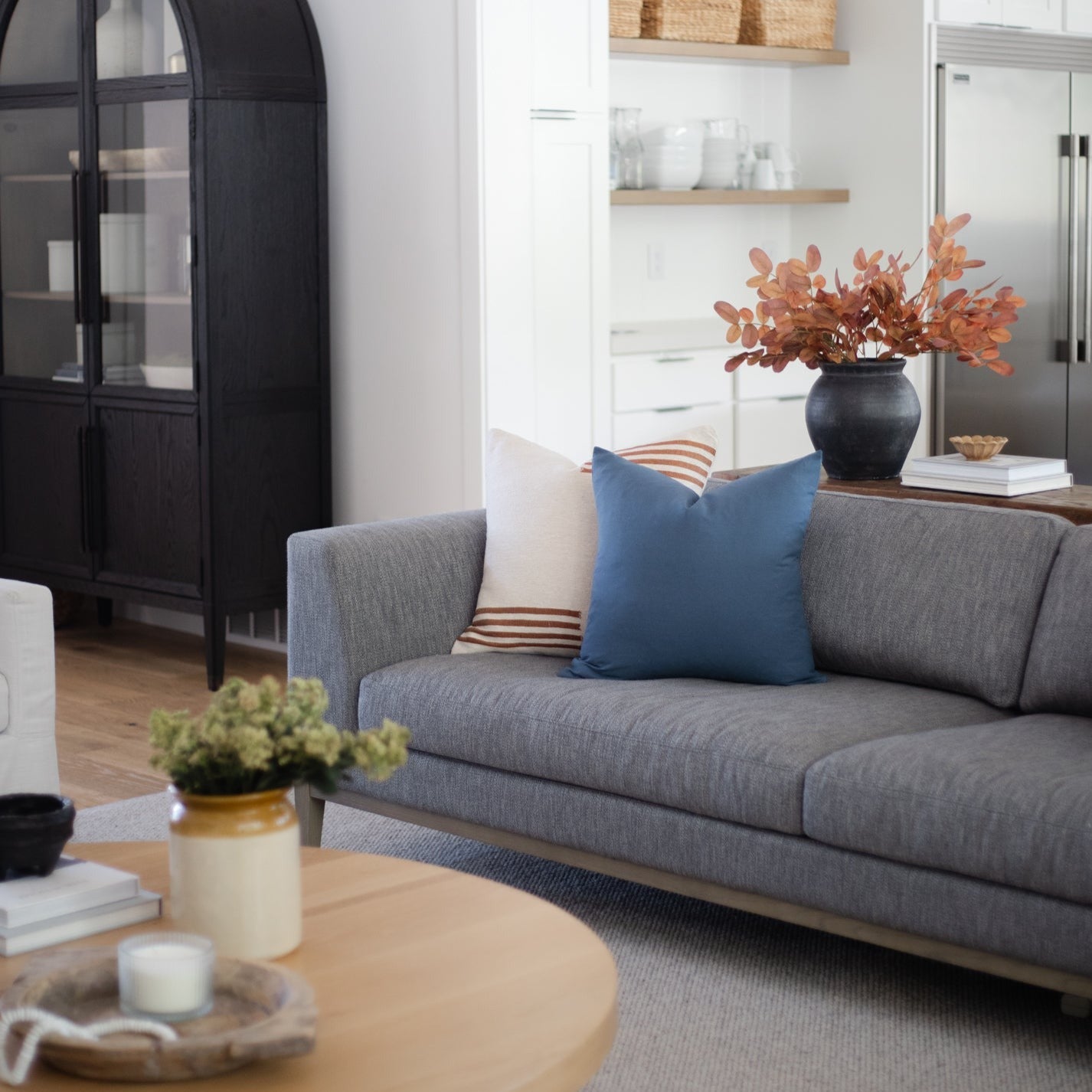 Navy blue square throw pillow on gray sofa in living room setting.