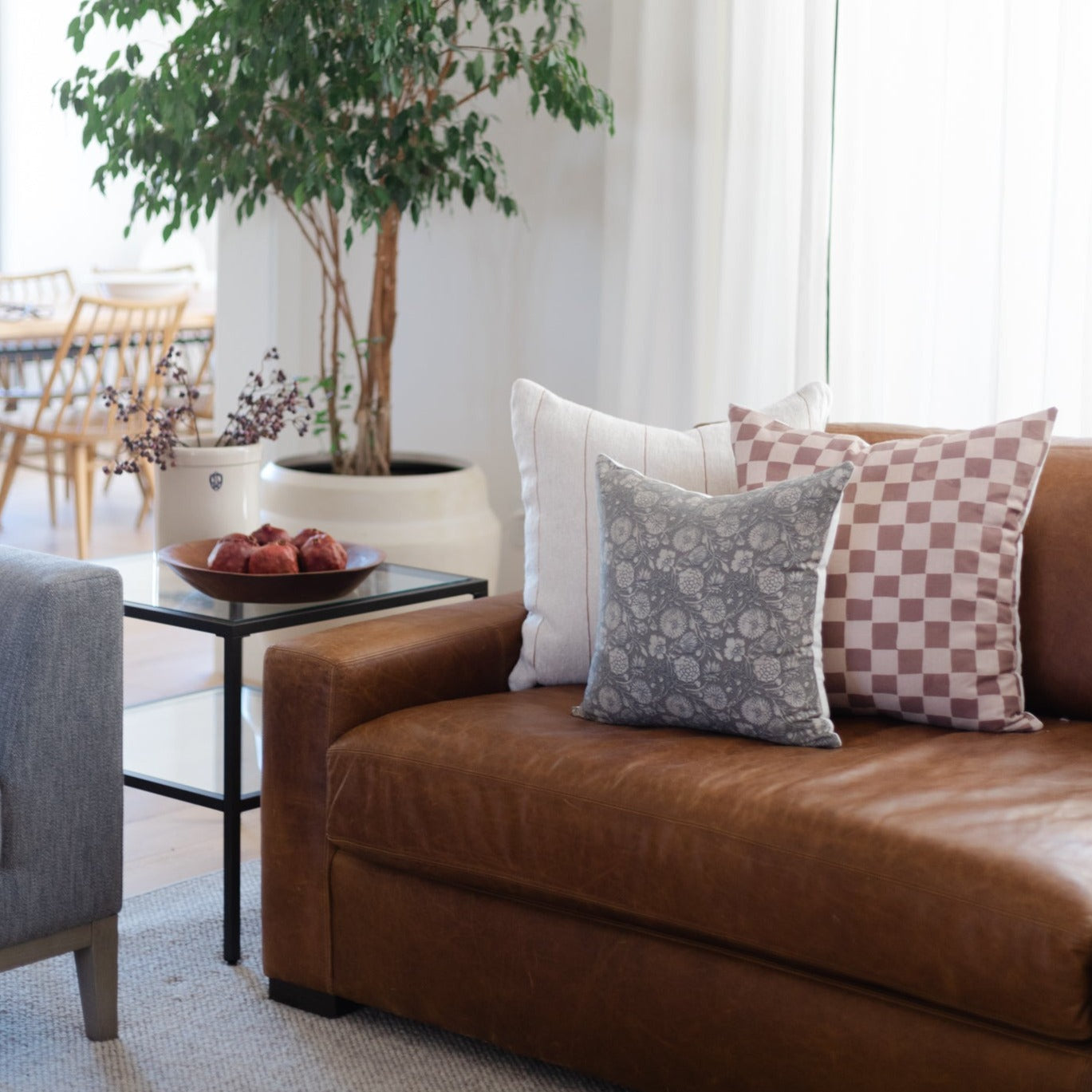 Brown leather sofa with decorative pillows in patterned and solid designs.