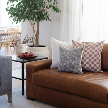 Brown leather sofa with decorative pillows in patterned and solid designs.