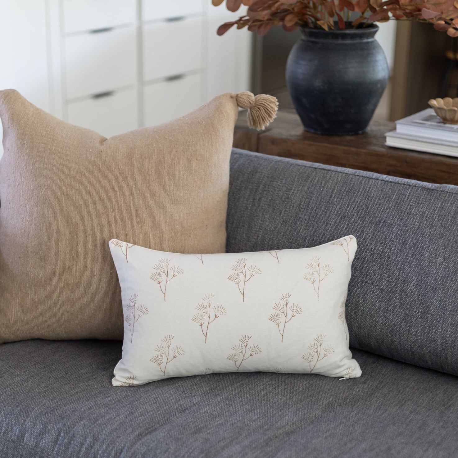 Rectangular lumbar pillow with cream background and repeating thistle flower pattern in taupe.