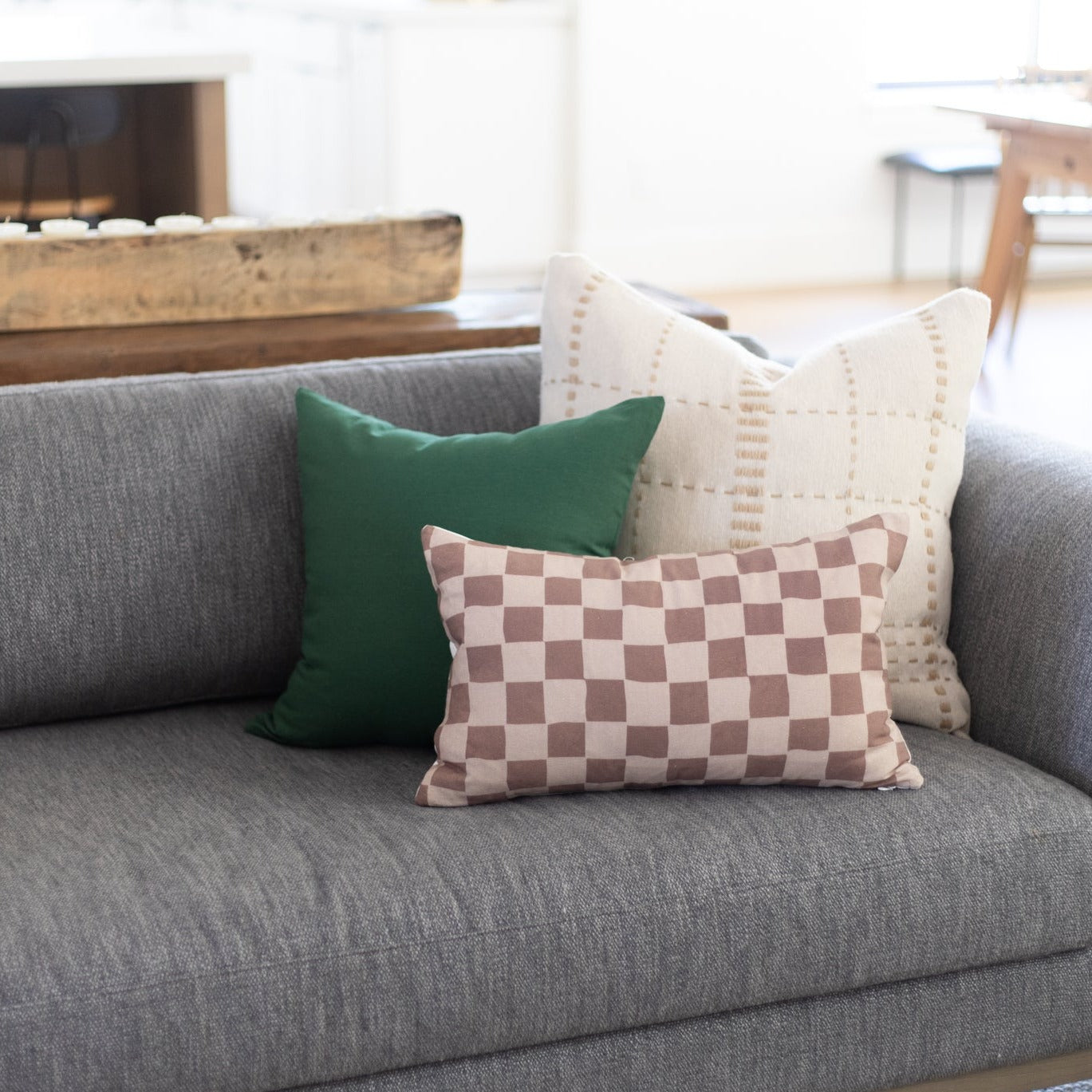 Rectangular lumbar pillow with tan and brown checkered pattern displayed on gray sofa.
