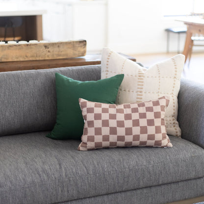 Rectangular lumbar pillow with tan and brown checkered pattern displayed on gray sofa.