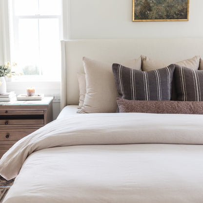 Colette lumbar pillow with charcoal and cream striped pattern displayed on bed with coordinating bedding.