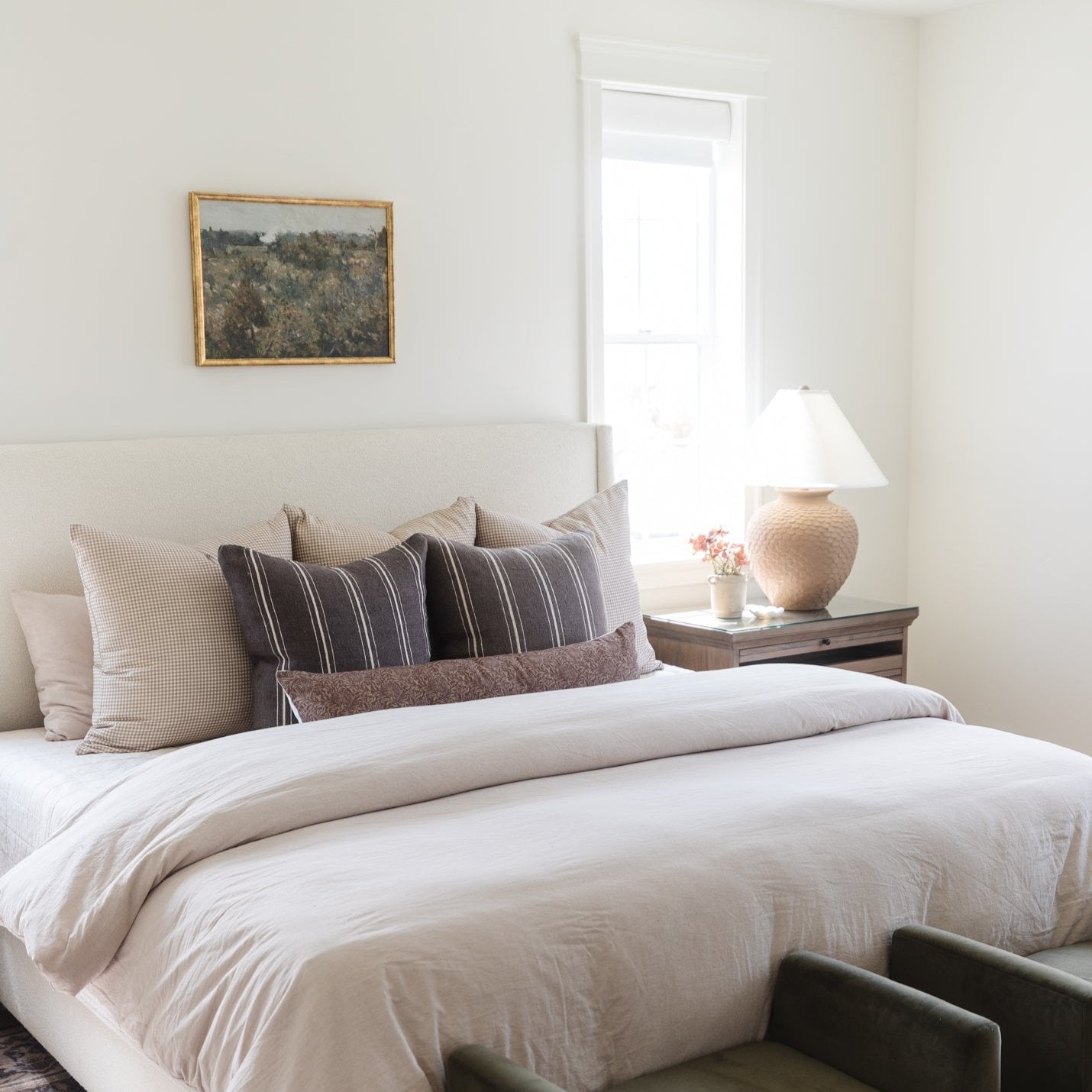 Striped lumbar pillow in dark gray and cream displayed on a bed with coordinating neutral pillows.