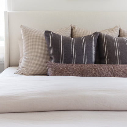 Rectangular lumbar pillows in striped and checked patterns arranged on a bed headboard.