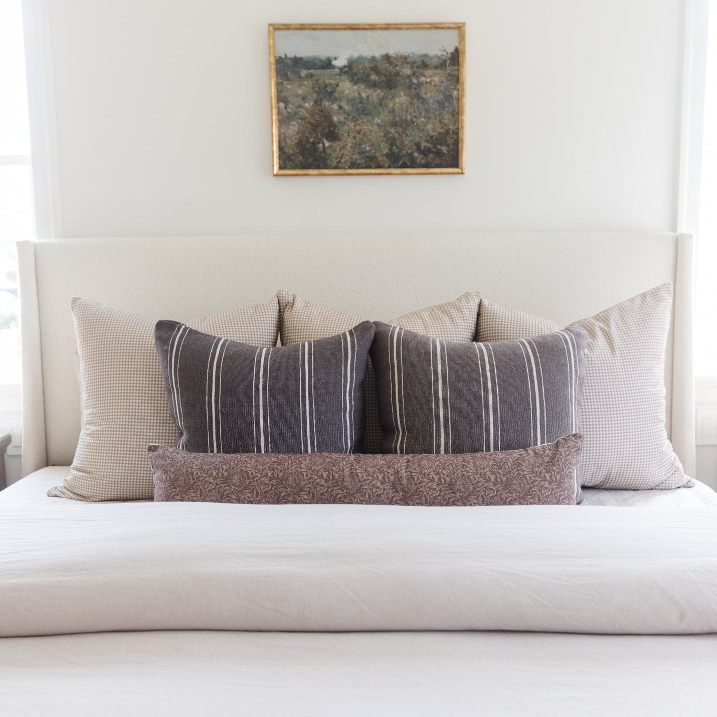 Gray striped lumbar pillow with white stripes displayed on a bed with coordinating pillows.