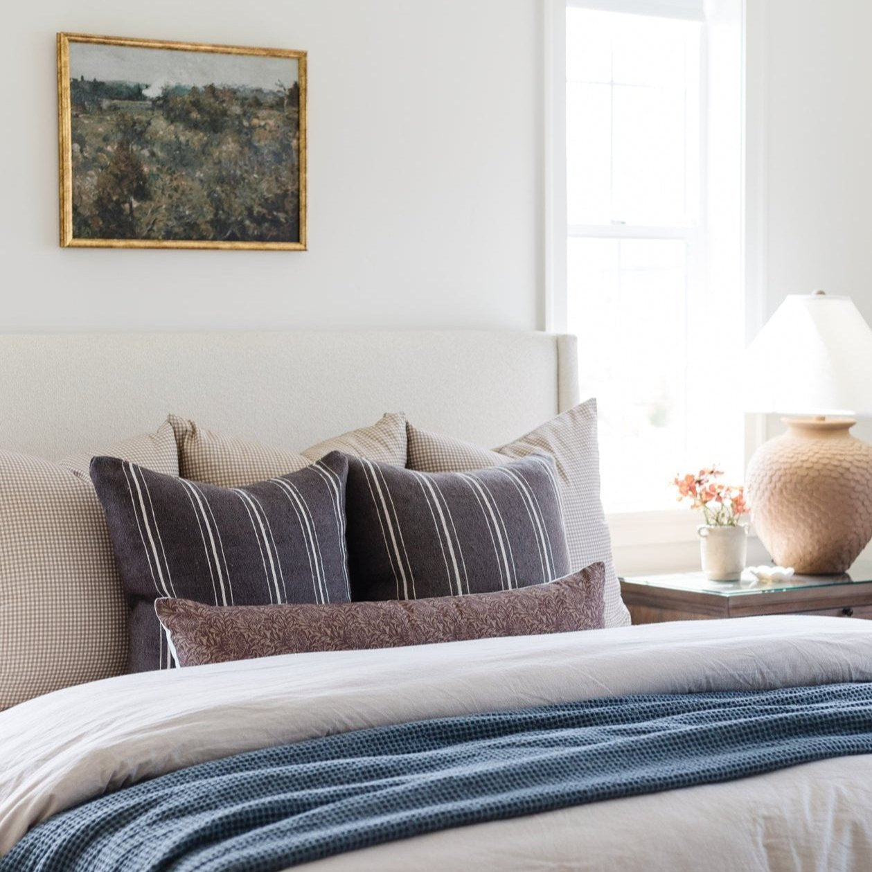 Rectangular lumbar pillow with navy blue and white vertical stripes, displayed on a bed with coordinating cushions.