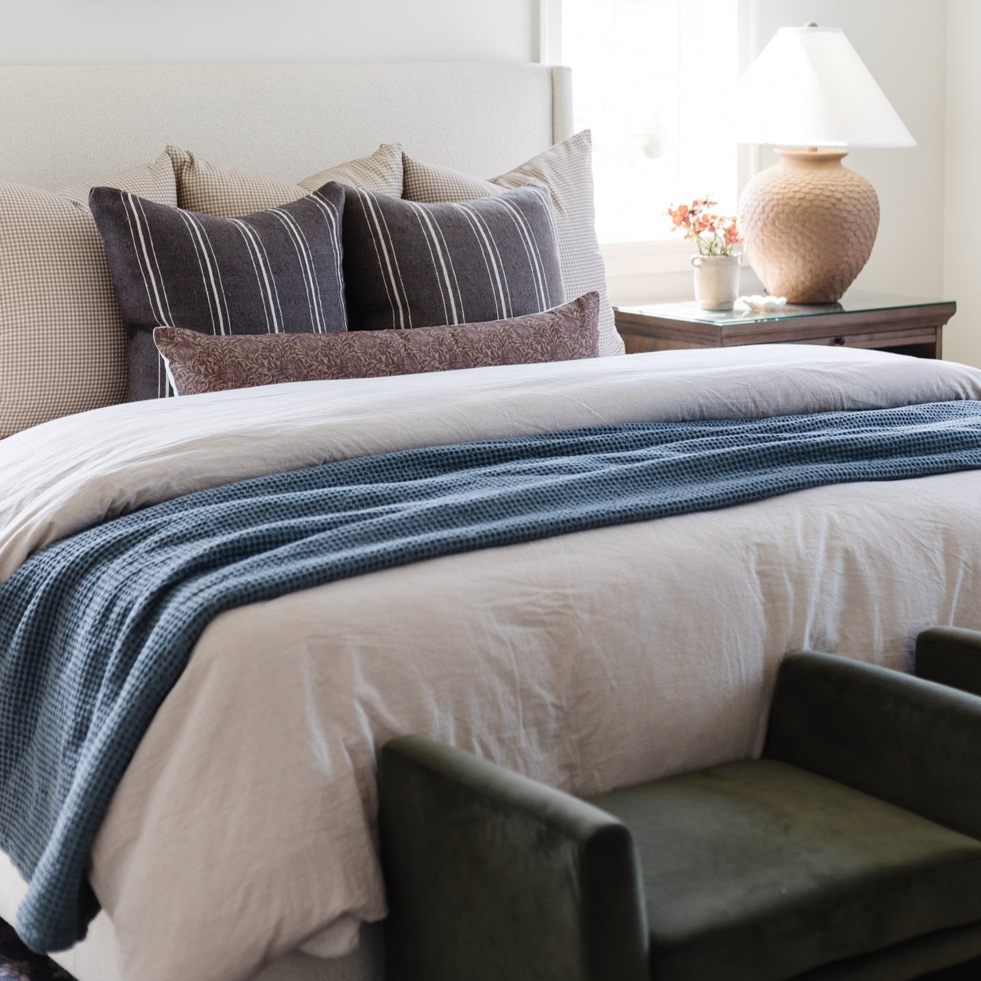 Storm blue waffle-textured blanket draped across a bed with white bedding and decorative pillows.