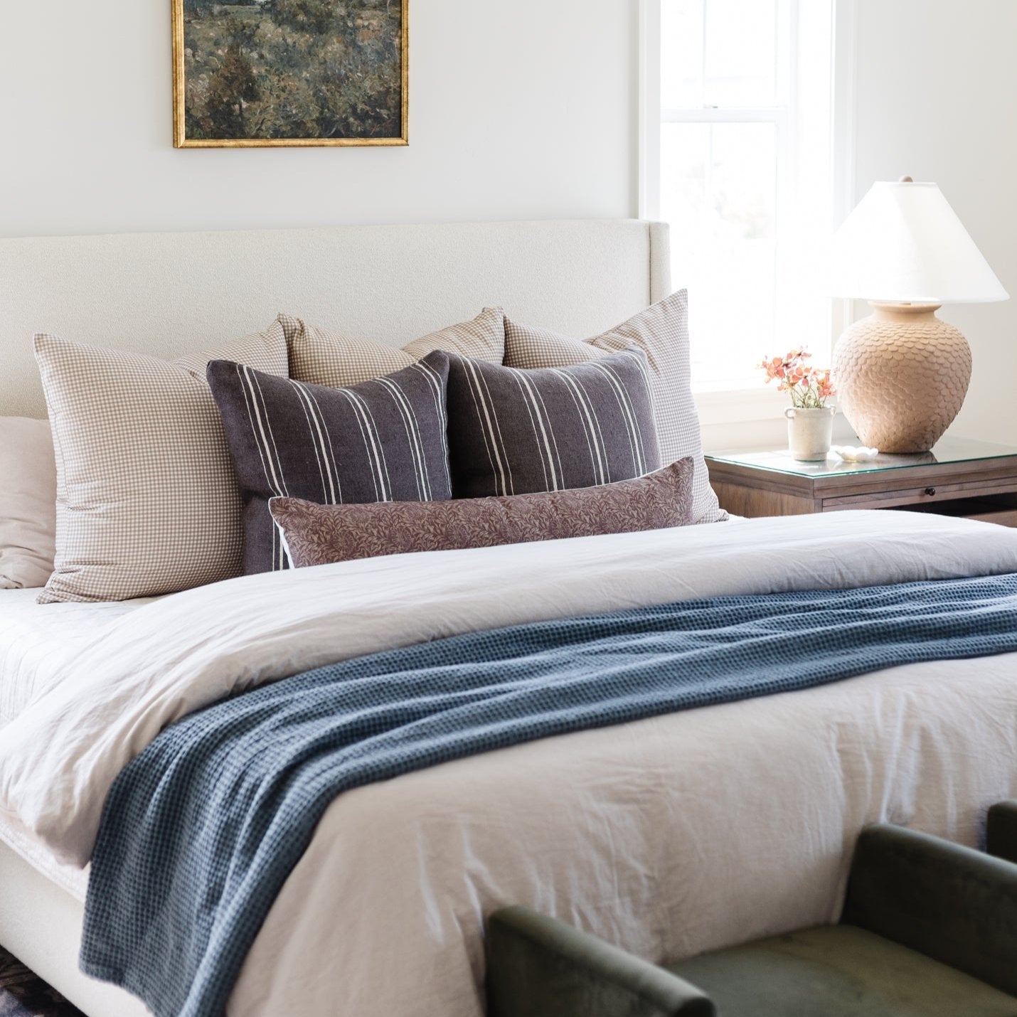 Colette lumbar pillow with navy vertical stripes and taupe accents displayed on a bed with coordinating neutral pillows.