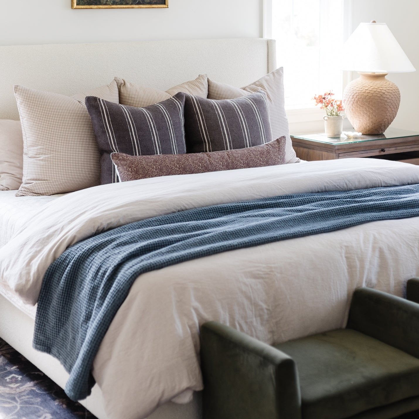 Storm blue waffle-textured blanket draped across a bed with white bedding and decorative pillows.