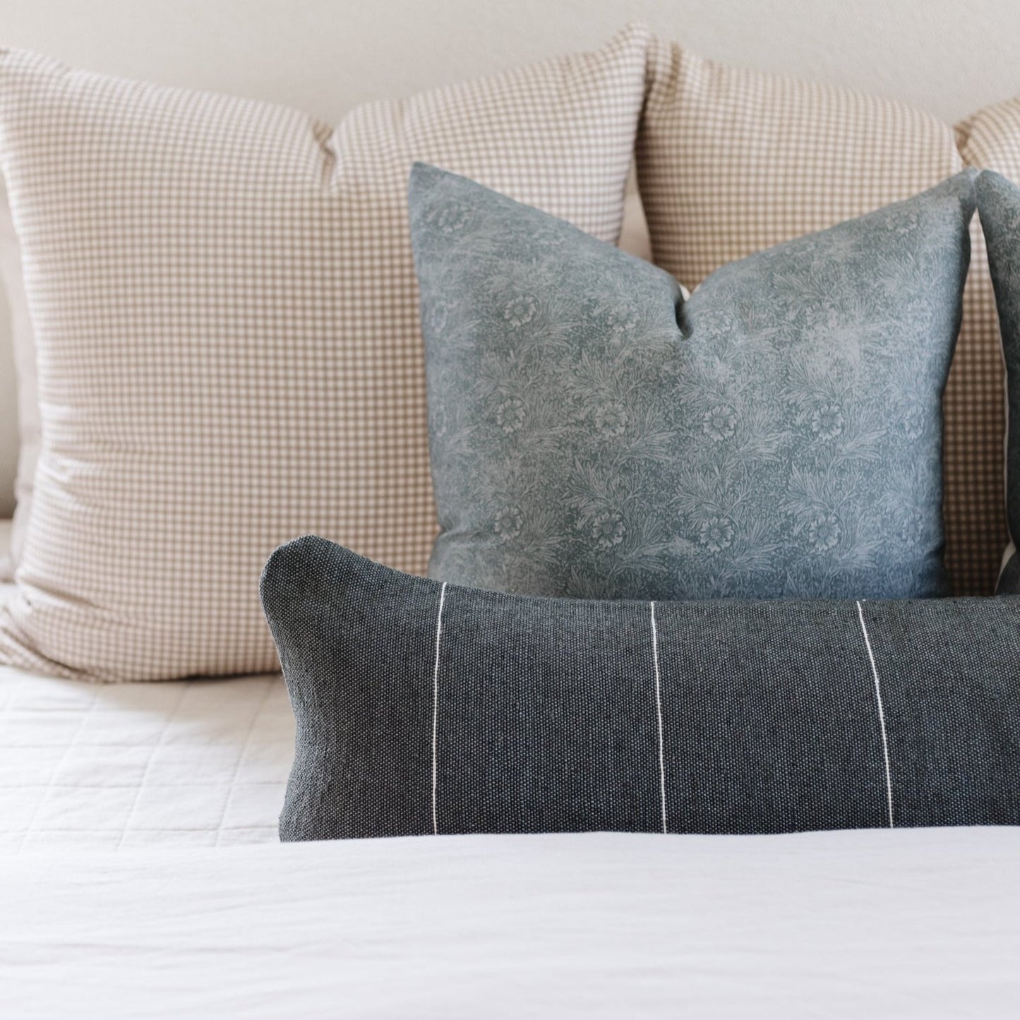 Rectangular lumbar pillow in charcoal gray with white vertical stripes, displayed with coordinating checkered and patterned p