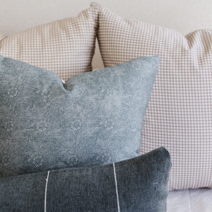 Three decorative pillows with gray floral print, gray textured solid, and beige gingham check patterns stacked together.