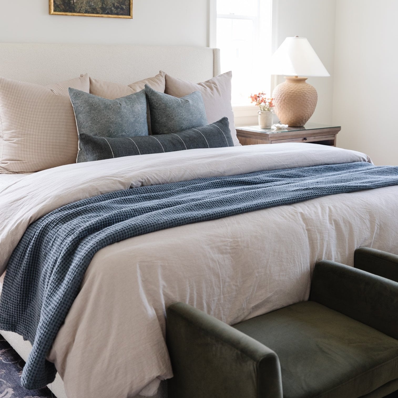 Storm blue waffle-textured blanket draped across a bed with white bedding and decorative pillows.